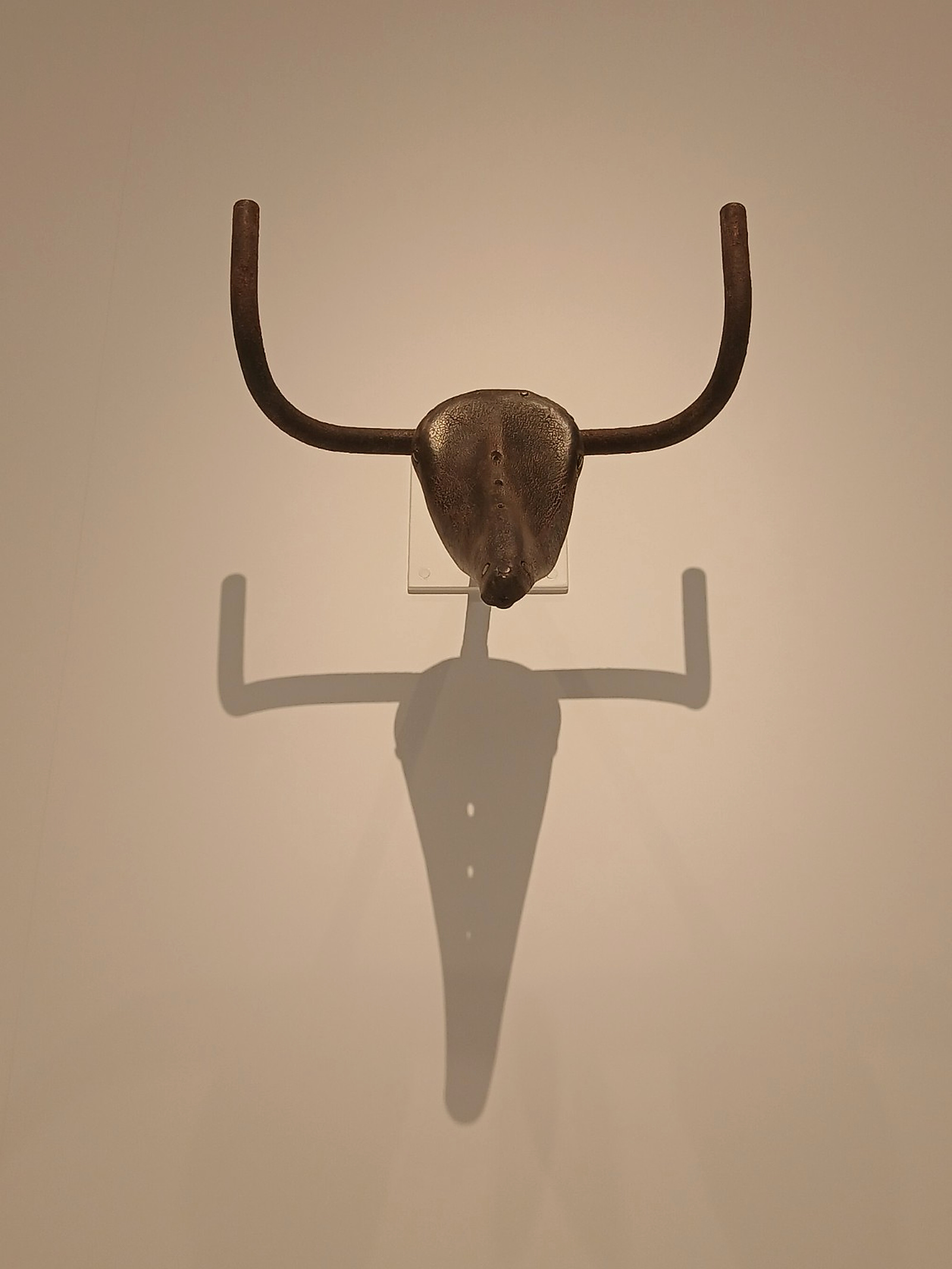 Picasso’s Bull’s Head, assembled from a bicycle seat and handlebars, casts a long shadow on the gallery wall.